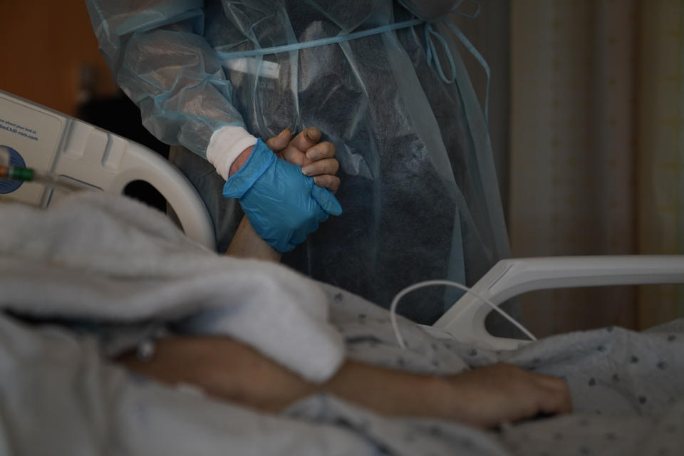 Chaplain Kristin Michealsen holds the hand of a deceased COVID-19 patient while talking on the phone with the patient's family member at Providence Holy Cross Medical Center in the Mission Hills section of Los Angeles on Saturday, Jan. 9, 2021. "I have never seen this much of death and suffering," said Michealsen, who has been a chaplain for 13 years. "I often tell families that I'm holding their loved one's hand when they can't and that I am with them when they are dying when they can't be." (AP Photo/Jae C. Hong)