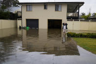 A woman stands in her flooded front yard of her home at Windsor on the outskirts of Sydney, Australia, Tuesday, July 5, 2022. Hundreds of homes have been inundated in and around Australia’s largest city in a flood emergency that was threatening 50,000 people, officials said on Tuesday. (AP Photo/Mark Baker)