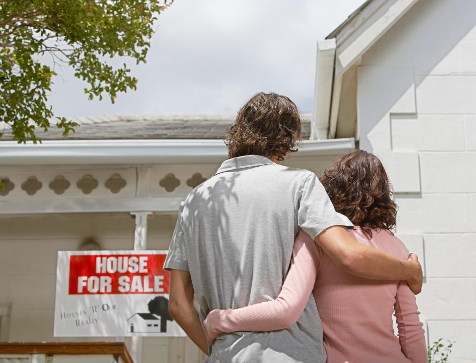 Couple in front of house for sale sign