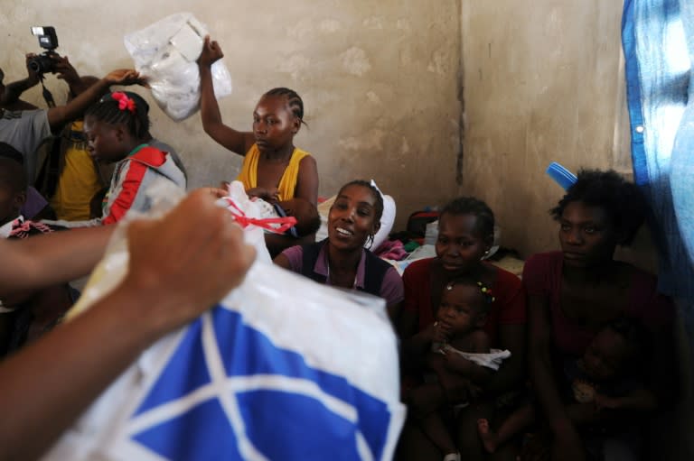 Beltha Desir (C) receives handouts from an NGO at a school in Fond Parisien, Haiti, on July 3, 2015, where she has been staying with her child since being deported from the Dominican Republic