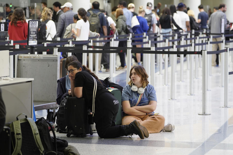 Travelers sit on the ground at the departure area at the United Airlines terminal at Los Angeles International Airport, Wednesday June 28, 2023, in Los Angeles. Travelers waited out widespread delays at U.S. airports on Tuesday, an ominous sign heading into the long July 4 holiday weekend, which is shaping up as the biggest test yet for airlines that are struggling to keep up with surging numbers of passengers. (AP Photo/Damian Dovarganes)