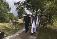 Pakistan's Foreign Minister Shah Mahmood Qureshi, left, and Defense Minister Pervez Khattak, walk in front of senior army officers during their visit to forward area post along a highly militarized frontier in the disputed region of Kashmir, in Chiri Kot sector, Pakistan, Monday, Aug. 3, 2020. The region's top Pakistani military commander briefed ministers about Indian cease-fire violations in Kashmir, which is split between Pakistan and India and claimed by both in its entirety. (AP Photo/Anjum Naveed)