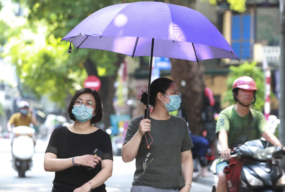 Women wearing face masks walk on the street in Hanoi, Vietnam, Thursday, July 30, 2020. Vietnam on Thursday reported several more cases of COVID-19, as the first outbreak in over three months spread to cities while authorities say they cannot trace its source. (AP Photo/Hau Dinh)