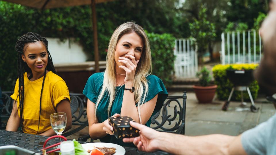 Happy young woman covering mouth while receiving gift by man.