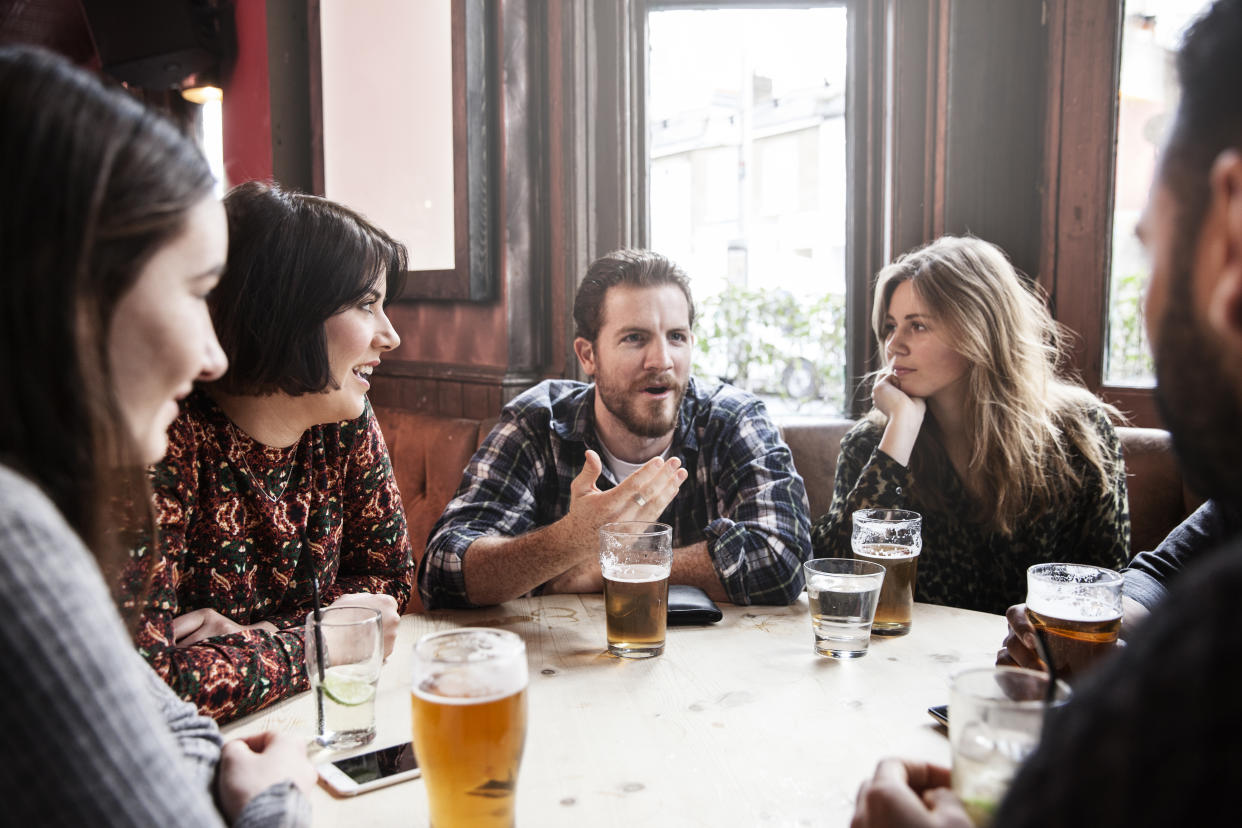 Group of friends at a pub having a discussion while drinkings beeers