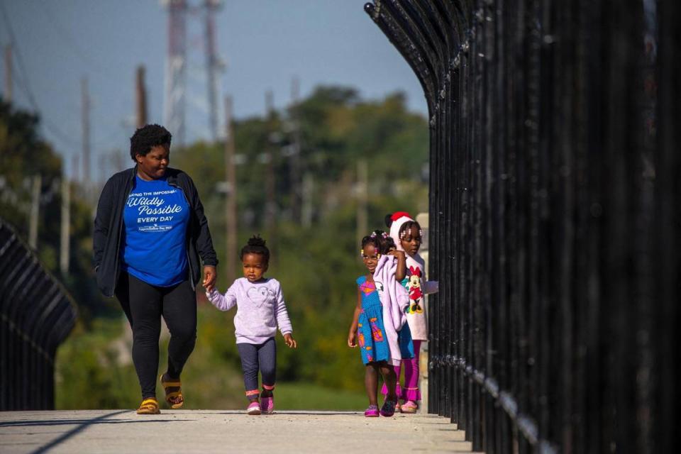 Claudette Chigede, of Lexington, walks with her daughters, from left, Olivia, 2, Amy, 4, and Joy, 5, over the Brighton Rail Trail pedestrian bridge over Man O’ War Boulevard in Lexington, Ky., on Monday, Sept. 27, 2021.