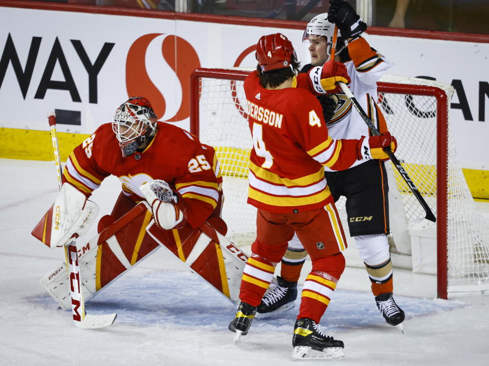 Anaheim Ducks forward Mason McTavish, right, is checked by Calgary Flames defenseman Rasmus Andersson, center, as Flames goalie Jacob Markstrom guards the net during first-period NHL hockey game action in Calgary, Alberta, Sunday, April 2, 2023. (Jeff McIntosh/The Canadian Press via AP)