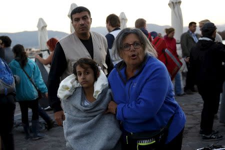 A volunteer escorts a rescued migrant girl after a boat carrying more than 200 refugees and migrants sunk while crossing part of the Aegean sea from Turkey, on the Greek island of Lesbos, October 28, 2015. REUTERS/Giorgos Moutafis