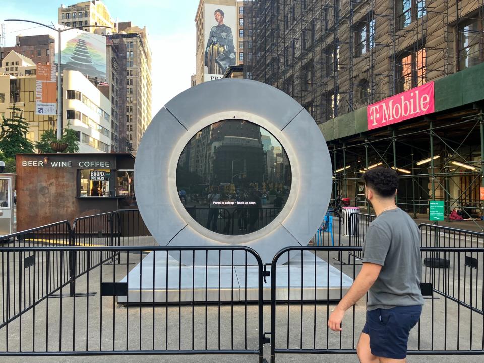 A person in casual attire walks past a large circular metallic structure the urban environment