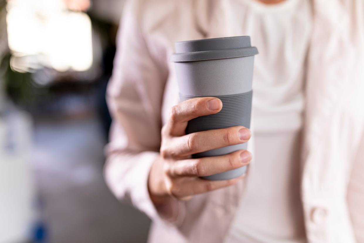 Close-up of a businesswoman holding recyclable takeaway coffee cup