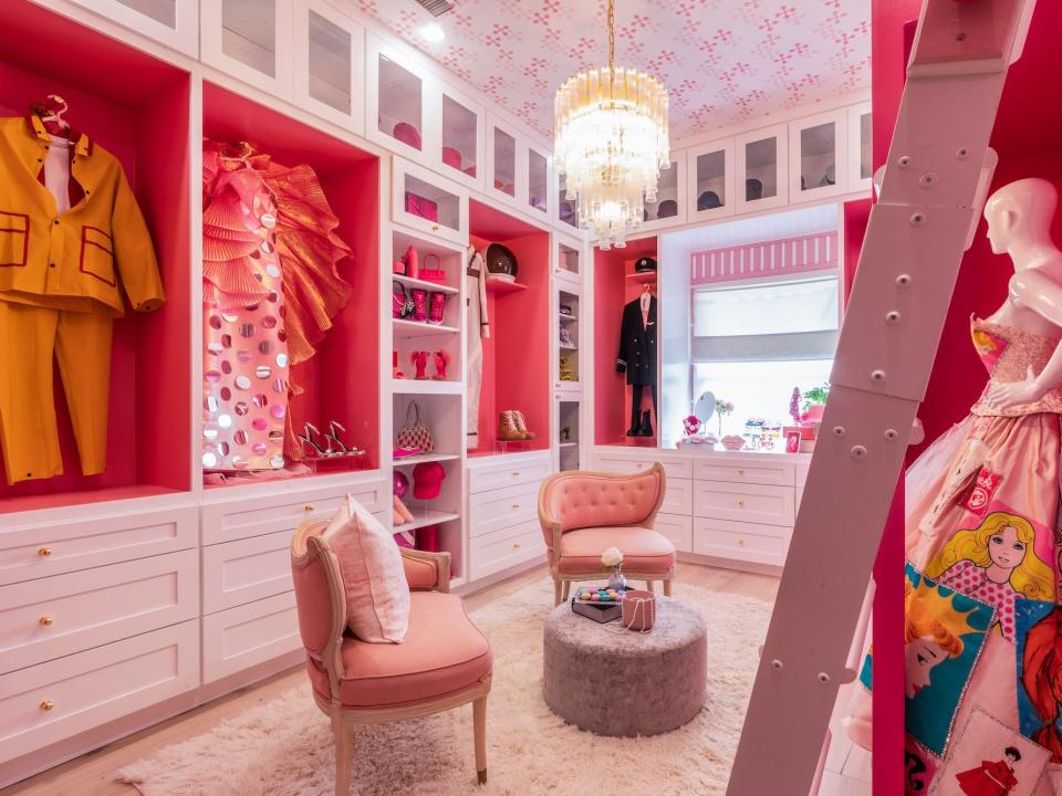 A pink, walk-in closet with outfits on display.