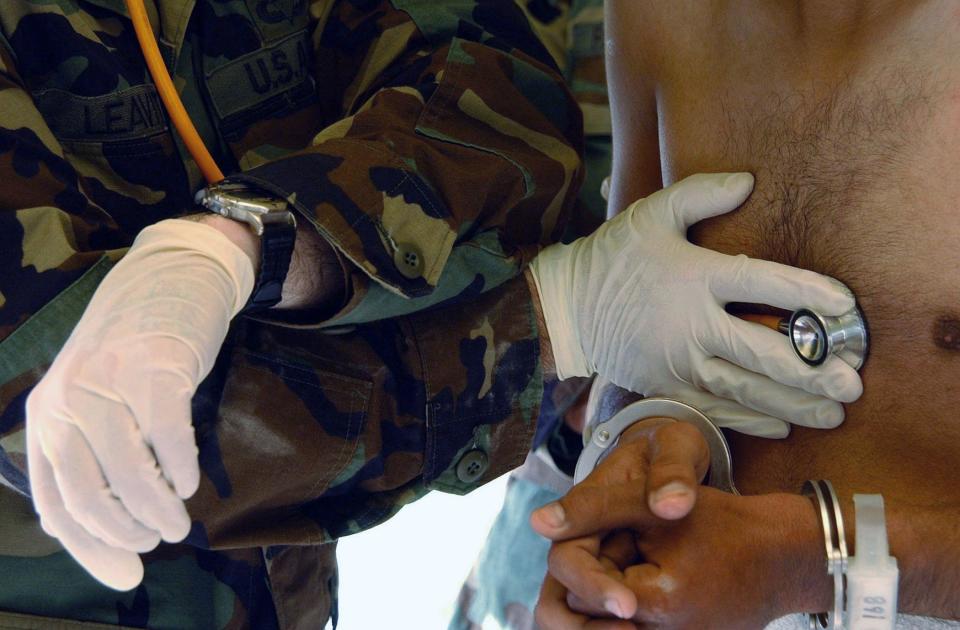 Un soldado ausculta a un detenido.