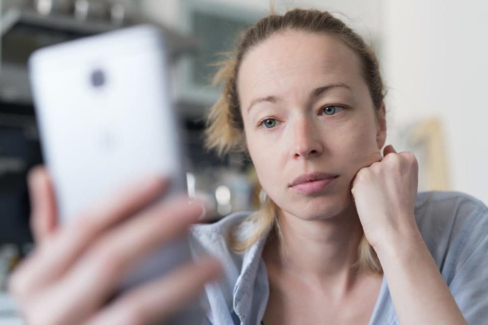 Mujer preocupada dentro de la cocina en casa usando aplicaciones de redes sociales en el teléfono para chatear por video y conectarse con sus seres queridos