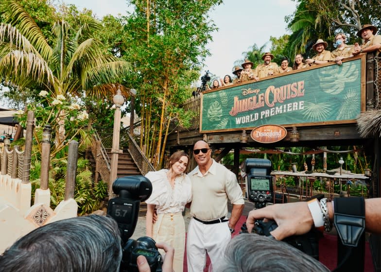 Anaheim, CA - 7/24/21: Emily Blunt and Dwayne Johnson exit the Jungle Cruise ride and pose for photographers on the red carpet for the premier of the new film Disney's Jungle Cruise while Disney cast members of the Jungle Cruise ride watch. Saturday, July 24, 2021 in Disneyland. (PHOTOGRAPH BY ADAM AMENGUAL / FOR THE TIMES)