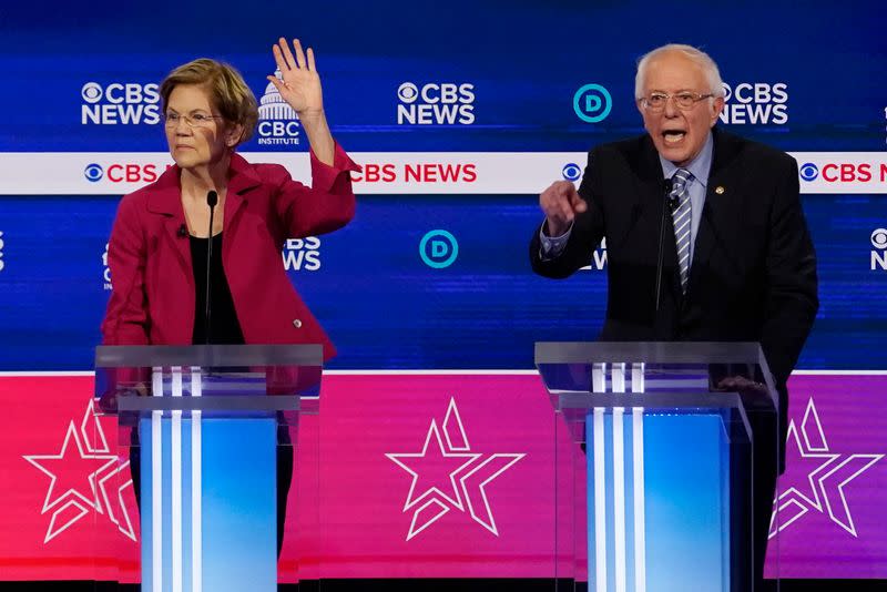 Senator Elizabeth Warren raises her hand as Senator Bernie Sanders speaks during the tenth Democratic 2020 presidential debate at the Gaillard Center in Charleston, South Carolina, U.S.