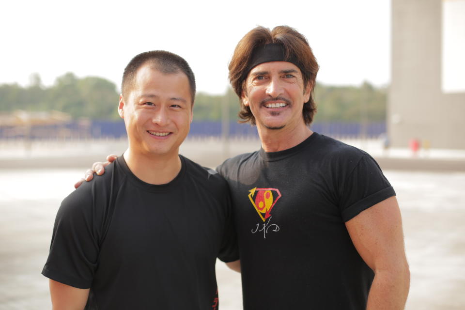 In this photo taken on Friday, March 7, 2014, provided by Brian Ho, stunt man Ju Kun, left, poses with John Fusco, creator of the show "Marco Polo" on the back lot of the new Pinewood Studios in Johor Bahru, Malaysia. Ju Kun, whose credits include the acclaimed martial arts epic "The Grandmaster," was among the passengers on the Malaysia Airlines plane that disappeared early Saturday, March 8, 2014. Ju Kun was scheduled to work on the series pilot for “Marco Polo,” a joint Weinstein Co. and Netflix production, at the studio in Malaysia before he boarded the flight to return home to Beijing. (AP Photo/Brian Ho) NO SALES, NO ARCHIVES, MANDATORY CREDIT, ONE TIME USE ONLY