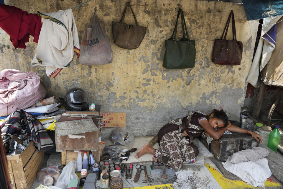 A cobbler rests by her work equipment on a hot summer day in Lucknow, India, Monday, May 27, 2024. (AP Photo/Rajesh Kumar Singh)