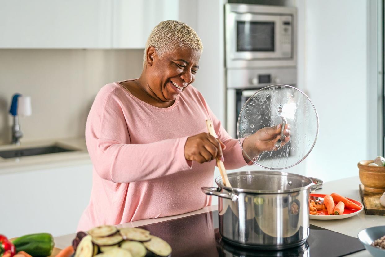 Happy senior woman preparing lunch in modern kitchen - Hispanic Mother cooking for the family at home