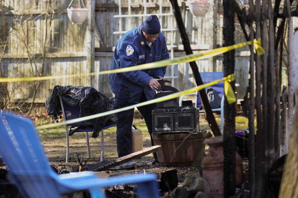 A fire official sorts through some items after a fatal fire early Sunday at 69 Hayward St. in Hopkinton, April 9, 2023.