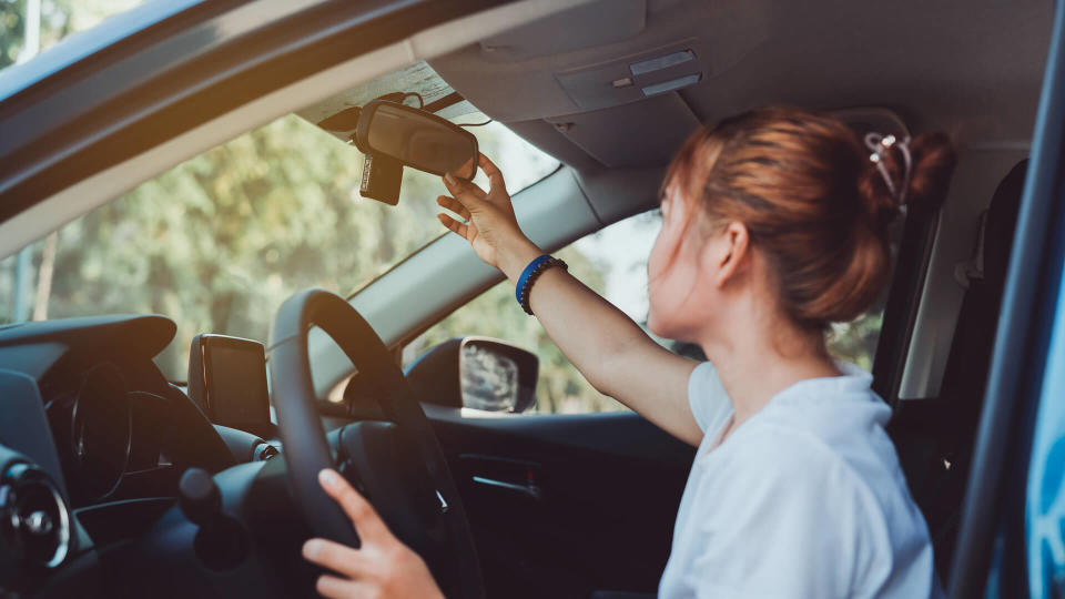 Safety driving woman adjust the car rearview mirror in interior before start travel trip every time.