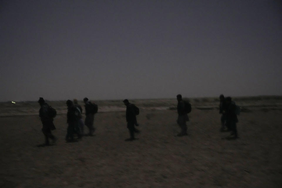 Young Shiite Afghan immigrants treck towards the the Iran-Afghanistan border wall in the desert around the city of Zaranj, Afghanistan, near the the Iran-Afghanistan border wall, to try to cross over the Iranian border wall into Iran, Monday, Dec. 25, 2023. Expulsions from Pakistan have swelled the already large numbers of Afghans who try to migrate into Iran, hoping to find work. (AP Photo/Ebrahim Noroozi)