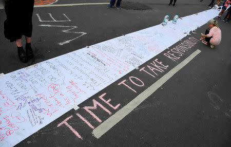 A woman draws a political slogan during the Extinction Rebellion protest on Oxford Street, near Marble Arch in London, Britain, April 22, 2019. REUTERS/Toby Melville