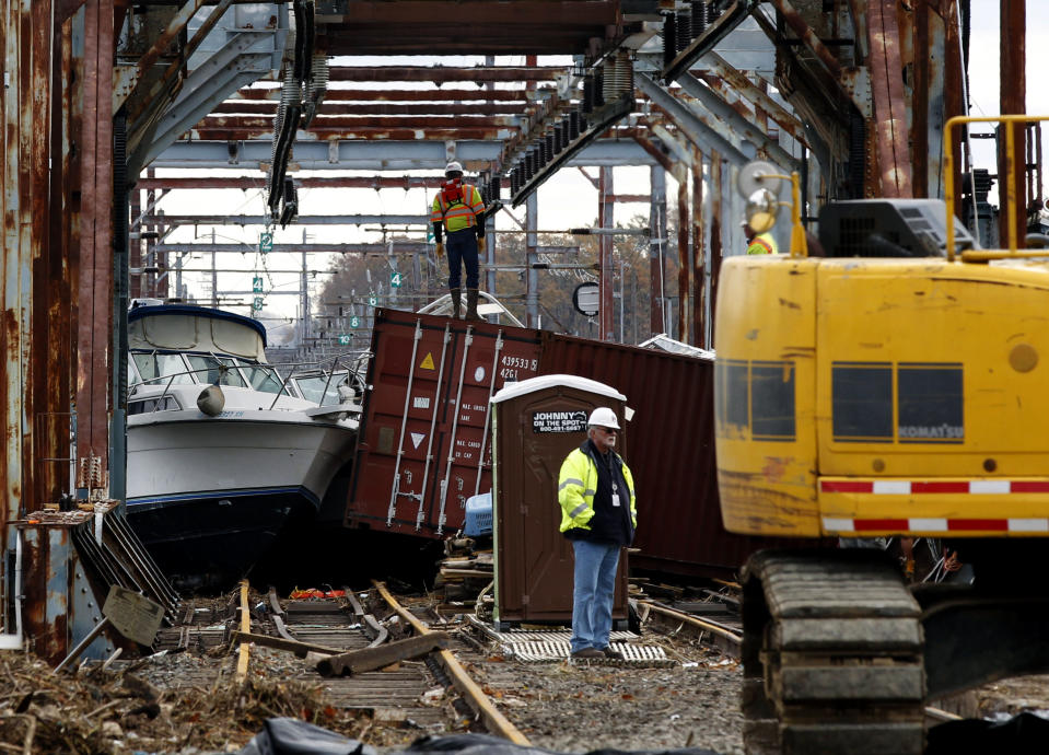 Workers try to clear boats and debris from the New Jersey Transit Morgan draw bridge Wednesday, Oct. 31, 2012, in South Amboy, N.J., after Monday's storm surge from Sandy pushed boats and cargo containers onto the train tracks. Travel in the Northeast creaked back into motion on Wednesday, a grinding, patchy recovery that made it clear that stranded travelers will struggle to get around for days to come. (AP Photo/Mel Evans)(AP Photo/Mel Evans)