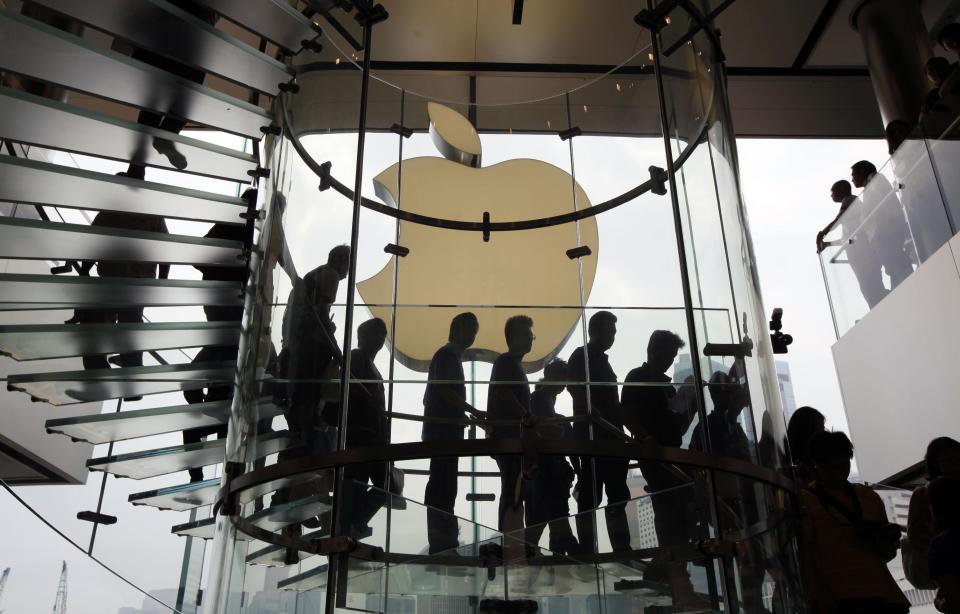 FILE - In this Sept. 24, 2011, file photo, customers walk past a huge Apple logo at the new store which is located on two floors linked by a glass spiral staircase in Hong Kong's upscale International Financial Center Mall. Friday, January 24, 2014, marks thirty years after the first Mac computer was introduced, sparking a revolution in computing and in publishing as people began creating fancy newsletters, brochures and other publications from their desktops. (AP Photo/Kin Cheung)