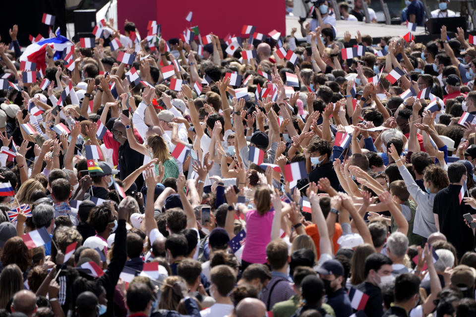People wave small flags and cheer in the Olympics fan zone at Trocadero Gardens in front of the Eiffel Tower in Paris, Sunday, Aug. 8, 2021. A giant flag will be unfurled on the Eiffel Tower in Paris Sunday as part of the handover ceremony of Tokyo 2020 to Paris 2024, as Paris will be the next Summer Games host in 2024. The passing of the hosting baton will be split between the Olympic Stadium in Tokyo and a public party and concert in Paris. (AP Photo/Francois Mori)