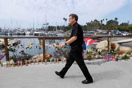 Father Lawrence Seyer, pastor of Our Lady of Mount Carmel Church in Montecito, walks past a makeshift memorial near Truth Aquatics as the search continues for those missing in a pre-dawn fire that sank a commercial diving boat near Santa Barbara, Californ