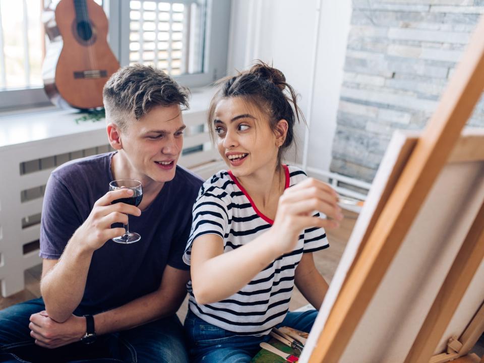 A couple looks at each other as they paint.