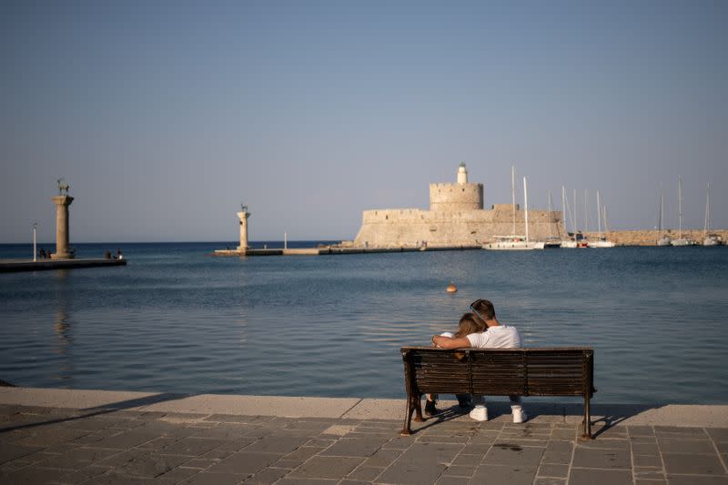 A couple sits on a bench in Mandraki harbour, following the coronavirus disease (COVID-19) outbreak, on the island of Rhodes