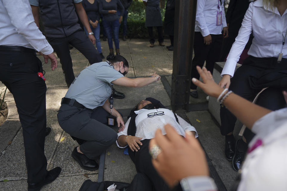 A woman is assisted for anxiety where people gather outside after a magnitude 7.6 earthquake was felt in Mexico City, Monday, Sept. 19, 2022. There were no immediate reports of damage from the quake that hit at 1:05 p.m. local time, according to the U.S. Geologic Survey, which said the quake was centered near the boundary of Colima and Michoacan states. (AP Photo/Fernando Llano)