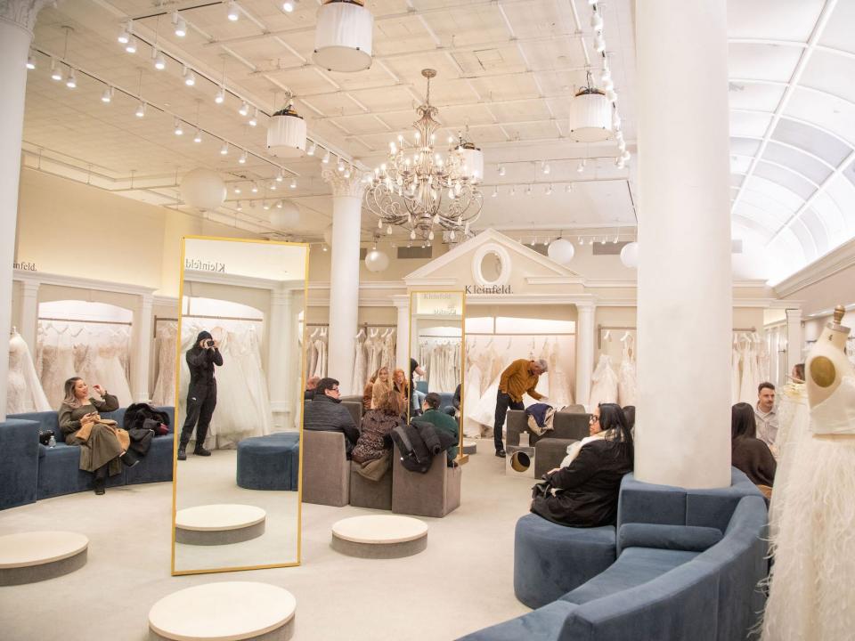 A bridal store with pedestals and blue couches.