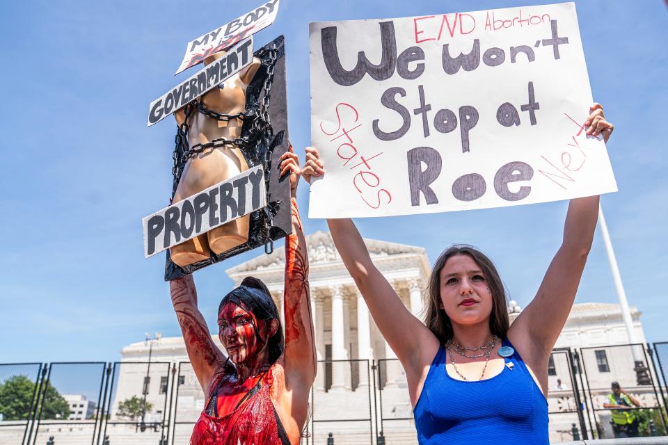 Abortion access supporter Sam Scarcello, left, and anti-abortion activist Elianna Geertgens hold competing signs in front of the Supreme Court on July 4, 2022, in Washington, D.C.