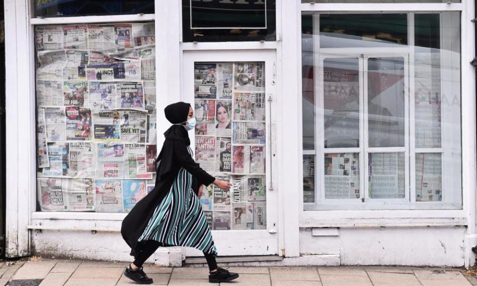 A woman walks past an empty, closed down shop in Newcastle-Under-Lyme, England.