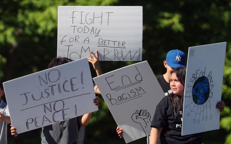 Students hold signs as they take part in the Eliminate Racial Violence march up Caldart Ave. to the North Kitsap School District building in Poulsbo on Thursday, May 18, 2023.