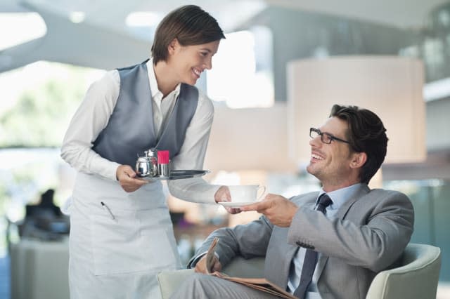 Waitress serving businessman cup of coffee in hotel lounge