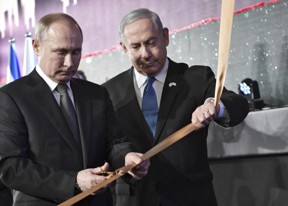 Russian President Vladimir Putin cuts a ribbon with Israeli Prime Minister Benjamin Netanyahu at an unveiling ceremony of the Remembrance Candle for World War II heroes of besieged Leningrad on Jan. 23, 2020 in Jerusalem. (Aleksey Nikolskyi / Sputnik via AP)