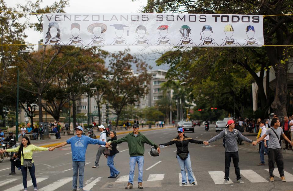 Manifestantes se toman de las manos para bloquear una avenida en el barrio de Altamira en Caracas, Venezuela, el lunes 24 de febrero de 2014. La capital venezolana amaneció el lunes en medio de nuevas tensiones luego de que decenas de manifestantes bloquearon algunas de las principales avenidas en protesta contra el gobierno, en medio de la crisis política que lleva tres semanas y ha dejado 12 muertos y más de un centenar de heridos. (AP foto/Rodrigo Abd)