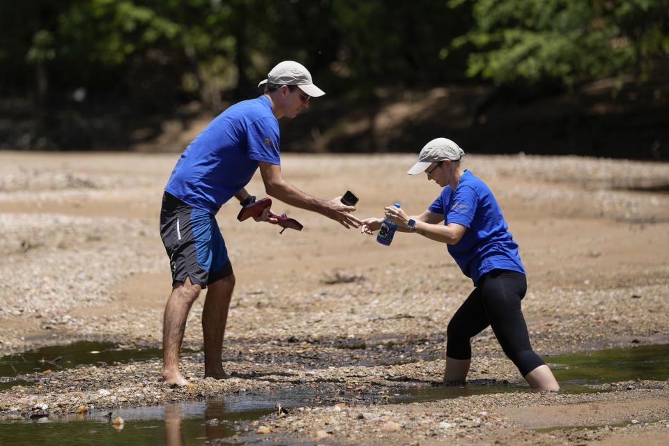 Biologist Cromwell Purchase helps his wife Candice walk on a dry stream at the Spix's macaws breeding facility project in a rural area of Curaca, Bahia state, Brazil, Monday, March 11, 2024. The South African couple is reintroducing the Spix’s macaw to nature through breeding and reintroduction efforts. (AP Photo/Andre Penner)