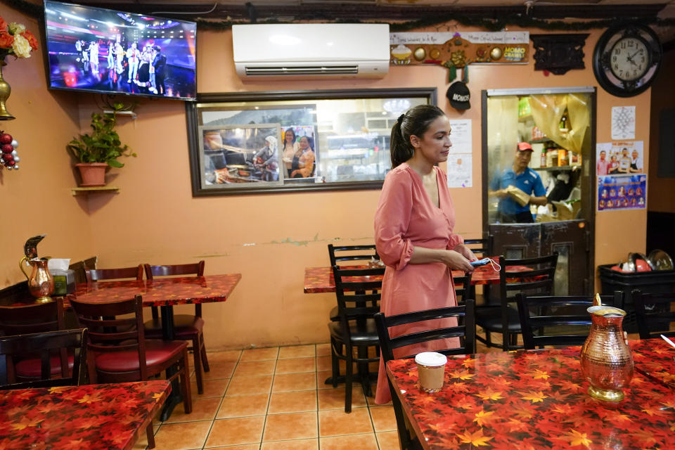 A kitchen worker at the Bhanchha Ghar looks at Rep. Alexandria Ocasio-Cortez, D-N.Y., as she arrives at the restaurant, Wednesday, July 6, 2022, in the Jackson Heights neighborhood of the Queens borough of New York. (As she seeks a third term this year and navigates the implications of being celebrity in her own right, she's determined to avoid any suggestion that she is losing touch with her constituents. AP Photo/Mary Altaffer)