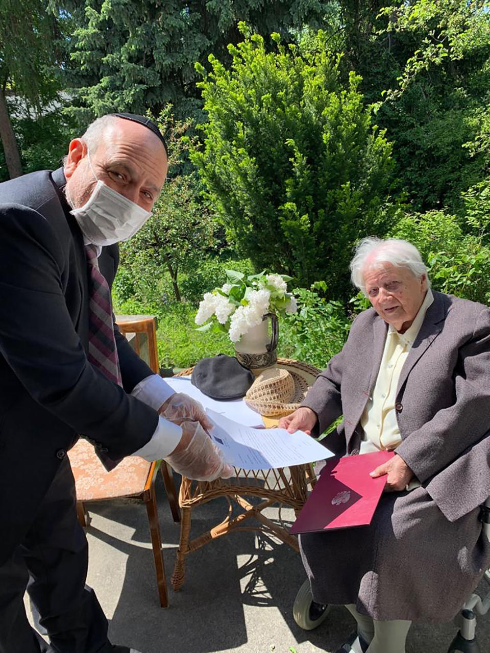 Poland's chief rabbi, Michael Schudrich, delivers letters with birthday greetings from the Israeli and Polish presidents, to Anna Kozminska, a 101-year-old Polish woman who is believed to the be oldest living person recognized by Yad Vashem for rescuing Jews during the Holocaust, in Warsaw, Poland, on Friday, May 22, 2020. Both Reuven Rivlin of Israel and Andrzej Duda of Poland praised Kozminska in letters for her courage in risking her own life help Jews during the German occupation of Poland. (Grazyna Pawlak via AP)