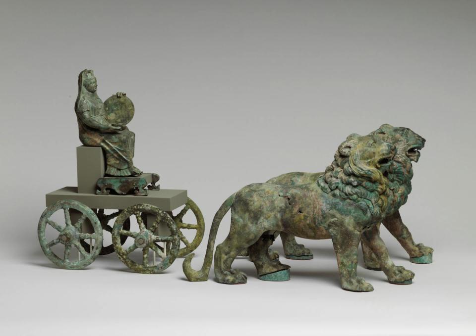 A bronze statuette of a woman riding a cart that is being drawn by two lions.