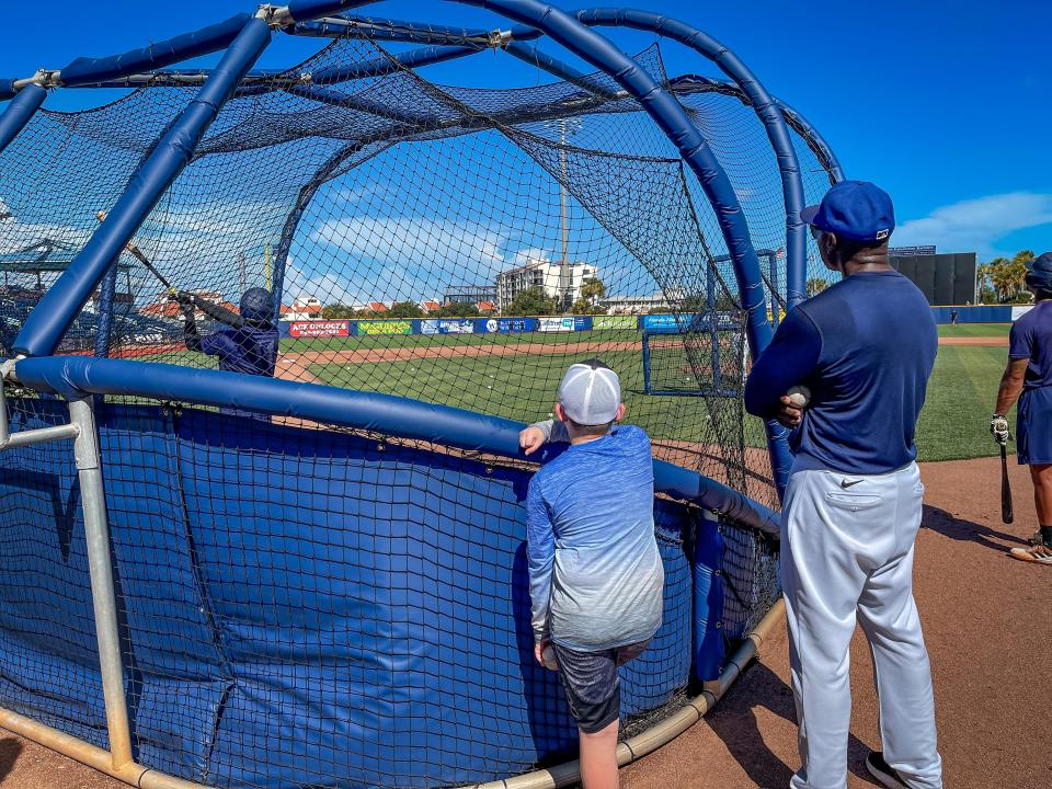 Hudson Furness, 10, whose mother Mandi is in Covenant Care Hospice with terminal illness, watches batting practice of his favorite Blue Wahoos player, Victor Victor Mess last Wednesday with first base coach Frank Moore next to him.