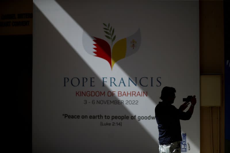 A man takes photos of a welcome poster of Pope Francis in Sacred Heart Catholic Church in Manama,