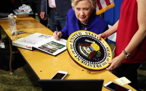 As she signs autographs, Democratic presidential candidate Hillary Clinton watches the World Series baseball game between the Chicago Cub and the Cleveland Indians after her final campaign rally of the day at Arizona State University in Tempe, Ariz., Wednesday, Nov. 2, 2016 - Credit: AP