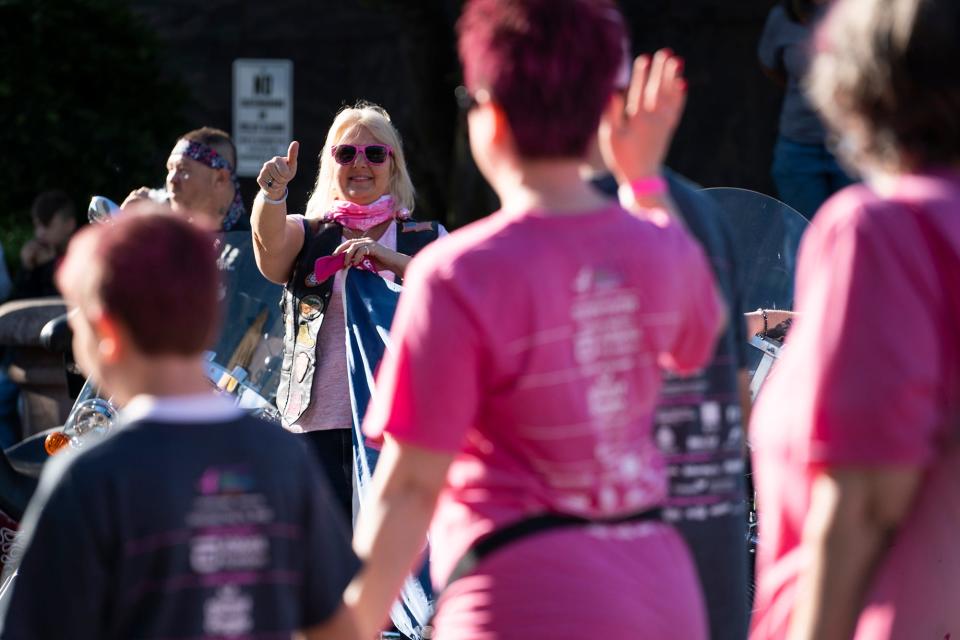 Susan Knorr, of Columbus, holds a "Love" sign and cheers on survivors and supporters Saturday at thunder alley at the start of the annual Komen Columbus Race for the Cure, which is back in person, after a two-year absence because of COVID-19.