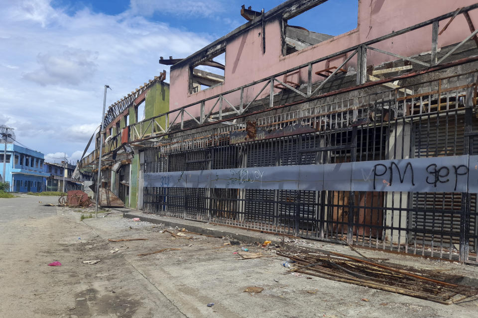 Graffiti written on the burnt out buildings from riots in Honiara's Chinatown from Nov. 2021, is seen in the Solomon Islands, Wednesday, March 30, 2022. Seeking to counter international fears over its new security alliance with China, the Solomon Islands said Friday, April 1, 2022 it won't allow China to build a military base there. (AP Photo/Charley Piringi)