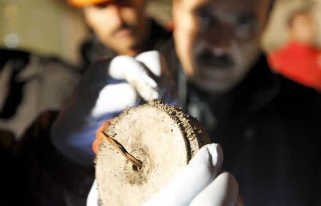 Police investigators collects metal fragments with a magnet at the ARY News offices after a blast injured several people and caused property damage in Islamabad, Pakistan January 13, 2016. REUTERS/Caren Firouz